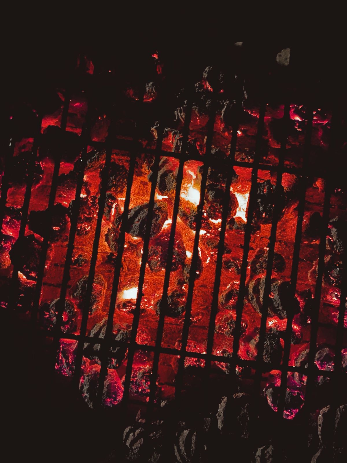 Glowing charcoal embers beneath the grill
