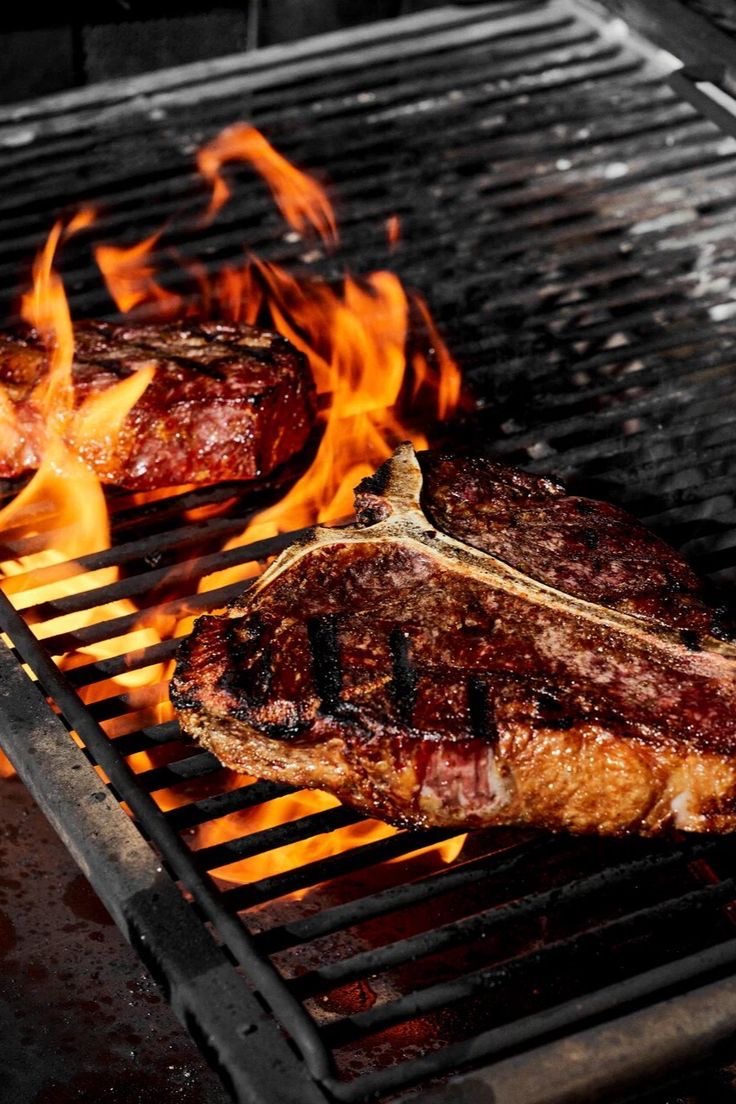 Steaks searing over open flames on the grill